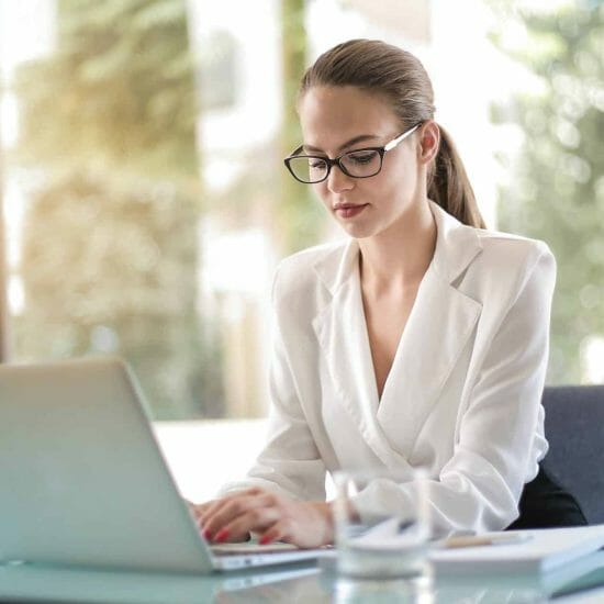 Concentrated female entrepreneur typing on laptop in workplace